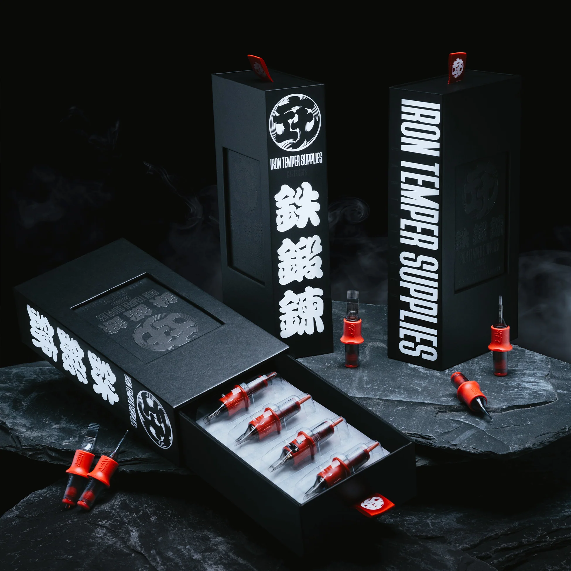 Three black Iron Temper boxes with red cartridges laid out on dark slate